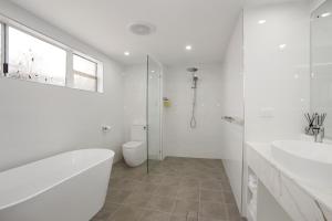 a bathroom with a tub and a toilet and a sink at Port Douglas Penthouse Suite in Port Douglas