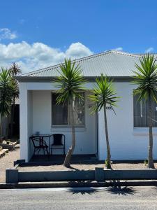 a white house with palm trees in front of it at Balan Village Motel in Nowra
