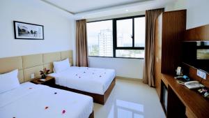 um quarto de hotel com duas camas e uma televisão em Alibaba em Nha Trang