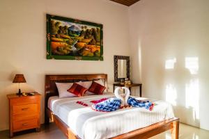 a bedroom with a bed and a painting on the wall at Alam Selumbung Garden in Nusa Penida