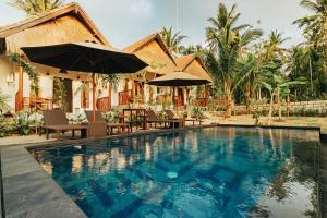 a pool with chairs and umbrellas in front of a house at Alam Selumbung Garden in Nusa Penida