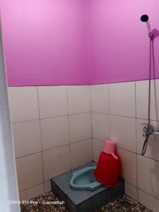 Baño pequeño con aseo y asiento rojo en Hotel Nakula Sadewa 2 Bandungan, en Semarang