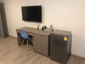 a wooden desk with a television and a blue chair at Neo Hotel in Khon Kaen