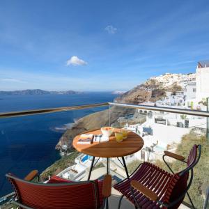 a table and chairs on a balcony overlooking the ocean at Panorama Boutique Hotel in Fira