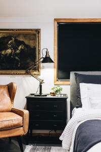 1 dormitorio con cama, lámpara y silla en Argentille Boutique Accommodation, en Rothbury