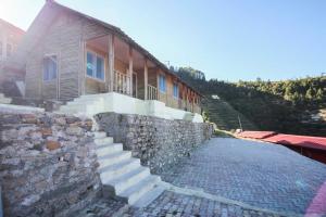 a stone wall next to a house with a stone staircase at Glamwood Resort Dhanaulti, Ranked 1 in Dhanaulti in Dhanaulti