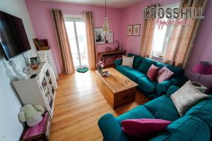 un soggiorno con divano blu e pareti rosa di CROSSHILL Appartements - Charmante und helle Wohnung a Schwandorf