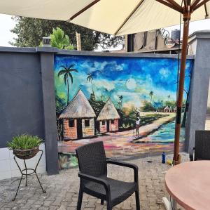 ein Gemälde an einer Wand mit Stühlen und einem Tisch in der Unterkunft ULOM 1condos apartment in Owerri