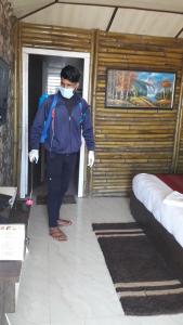 a man wearing a mask in a room with two beds at Glamwood Resort Dhanaulti, Ranked 1 in Dhanaulti in Dhanaulti