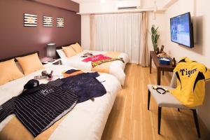 大阪市にある@RLiS_house大阪ドームシティのベッド2台とテレビが備わるホテルルームです。