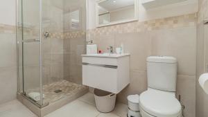 a bathroom with a toilet and a glass shower at Sea Breeze Guest House in Bloubergstrand