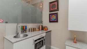 a kitchen with a sink and a microwave at Sea Breeze Guest House in Bloubergstrand