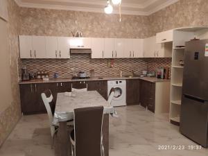 eine Küche mit weißen Schränken und einem Tisch mit Stühlen in der Unterkunft Family villa in Qabala in Qəbələ