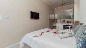 a bedroom with a white bed with flowers on it at Sea Breeze Guest House in Bloubergstrand