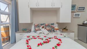 a bed with red flowers on it in a kitchen at Sea Breeze Guest House in Bloubergstrand +15 photos