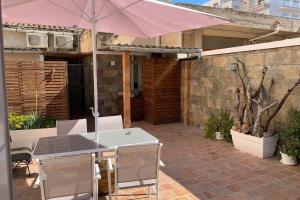 een patio met een parasol en een tafel en stoelen bij Casa antigua reformada junto al mar in El Arenal