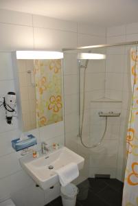 a white bathroom with a sink and a shower at Hotel Garni Bären Bazenheid in Bazenheid +16 photos
