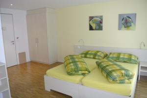 Schlafzimmer mit einem Bett mit gelber Bettwäsche und Kissen in der Unterkunft Hotel Garni Bären Bazenheid in Bazenheid