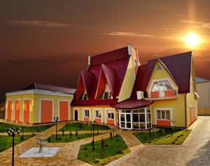 une maison avec un toit rouge et un coucher de soleil en arrière-plan dans l'établissement Гранд Алексік, à Trouskavets