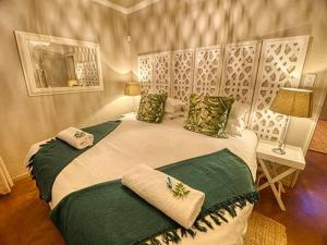 a bedroom with a large white bed with green pillows at Kruger park House in Hazyview