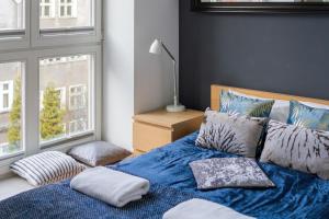 a bedroom with a blue bed with pillows and a window at Old Town Neptun Apartments by Renters in Gdańsk