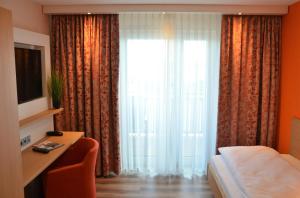 ein Hotelzimmer mit einem Bett und einem großen Fenster in der Unterkunft Hotel Bergwirt in Herrieden