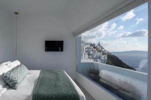 a bedroom with a large window with a view of the city at Panorama Suites in Fira