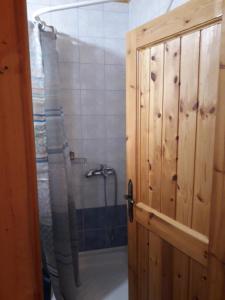 a bathroom with a shower and a wooden door at Mystic Lake in Koukkoúlion