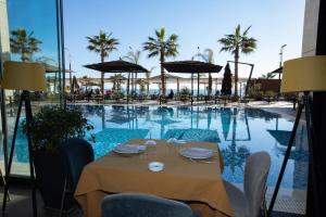 a dining table with chairs next to a swimming pool at Royal G Hotel & SPA 4 Star in Durrës