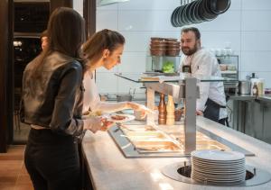 un hombre y dos mujeres parados en una cocina preparando comida en EFI SPA Hotel Superior & Pivovar en Brno