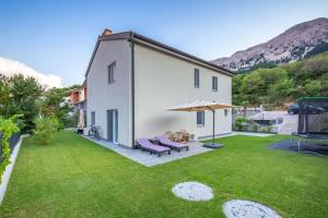 a large yard with a white house and an umbrella at Tarari Luxury Apartment in Baška