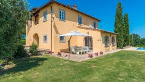 una casa con una mesa y una sombrilla en el patio en Villa Pucci 12, Emma Villas, en Monte San Savino
