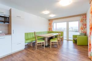 a dining room with a table and green chairs at Aparthotel am Reitecksee in Flachau