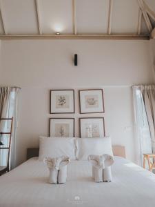 a bedroom with a white bed with two chairs at Sappraiwan Elephant Resort & Sanctuary in Kaengsopha