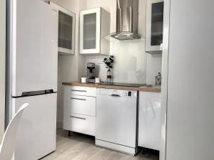 a white kitchen with a refrigerator and a dishwasher at Horizon Plage in Hyères