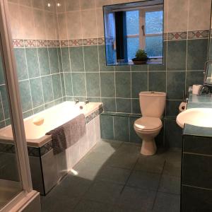 a bathroom with a tub and a toilet and a sink at The Miners Cottage in Whitecroft