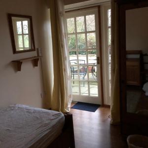 a bedroom with a bed and a door to a patio at The Miners Cottage in Whitecroft