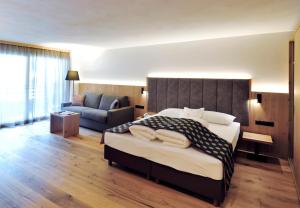 a bedroom with a large bed and a couch at Hotel Eller in Solda