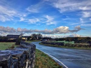 a road with a stone wall on the side of it at Entire cosy home from home country retreat in Holyhead