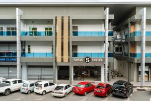 ein Parkplatz mit Autos vor einem Gebäude in der Unterkunft SVOK Hotel in Tawau