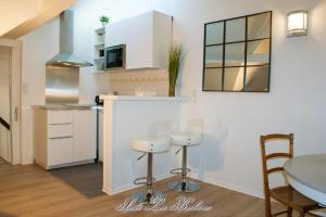 a kitchen with white cabinets and a table and chairs at La Venelle du Bassin in Honfleur