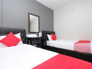 a bedroom with two beds with red pillows and a mirror at Elite Hotel in Kuantan