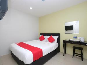 a bedroom with a bed with red pillows and a desk at Elite Hotel in Kuantan