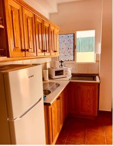 a kitchen with a white refrigerator and wooden cabinets at Apartamento La Real 2 in San Nicolás