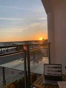 a laptop on a balcony with the sunset in the background at 南灣陽光皮小妞 Pii hostel in Nanwan