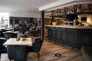 un restaurante con bar, mesas y sillas en Hotel Riche, en Valkenburg