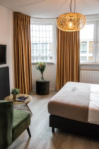 a bedroom with a bed and a chair and a window at Hotel Riche in Valkenburg