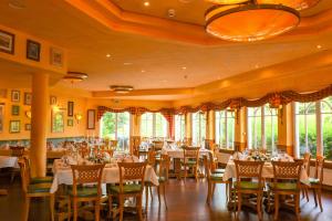 - une salle à manger avec des tables, des chaises et des fenêtres dans l'établissement Ringhotel Klövensteen, à Schenefeld