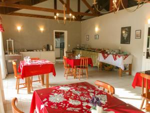 a dining room with red clothed tables and a kitchen at Pousada Tango in Gramado