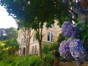 a large house with purple flowers in front of it at Westwell Hall Guest Accommodation, Bed & Breakfast, Luxury Rooms - Room Only Accommodation OR Self Catered Apartment in Ilfracombe